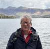 Photo of Barry Doyle, smiling, in front of a Lake District lake and mountains.